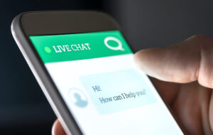 Le smartphone affiche le support technique "Live chat" avec une bulle de texte en dessous qui dit “Hi! How can I help you?”